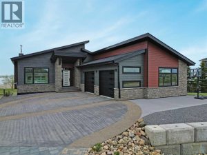The curb appeal stands out with composite siding, stone accents, and an oversized stamped concrete driveway, along with additional paved parking beside the garage ideal for an RV or guests