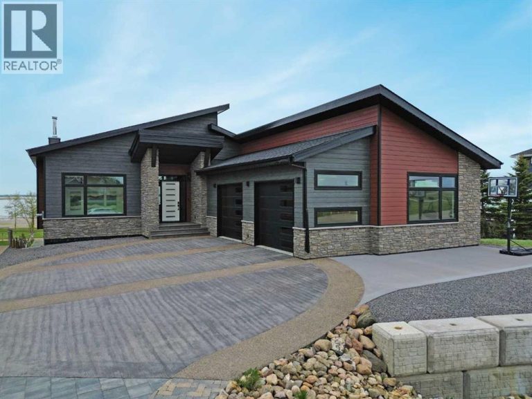 The curb appeal stands out with composite siding, stone accents, and an oversized stamped concrete driveway, along with additional paved parking beside the garage ideal for an RV or guests